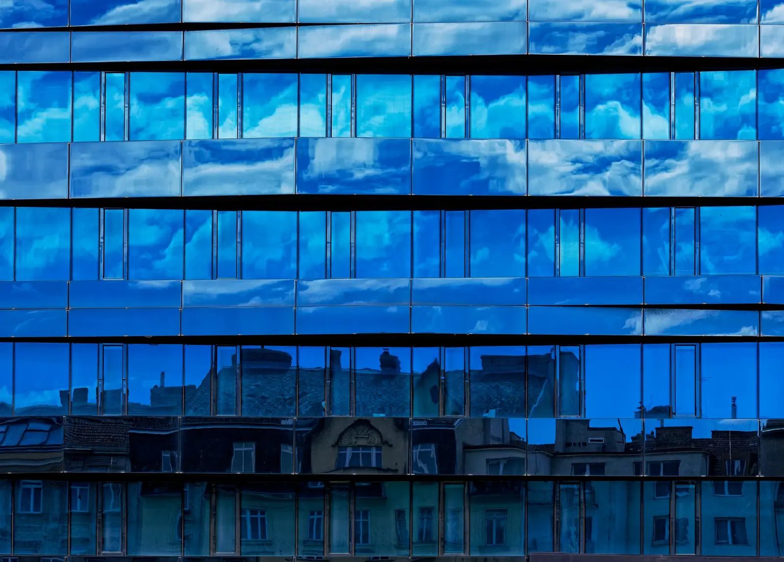 Fachada de cristal que refleja el cielo y los edificios de enfrente, el efecto que produce una pel&iacute;cula tipo espejo vista desde la calle