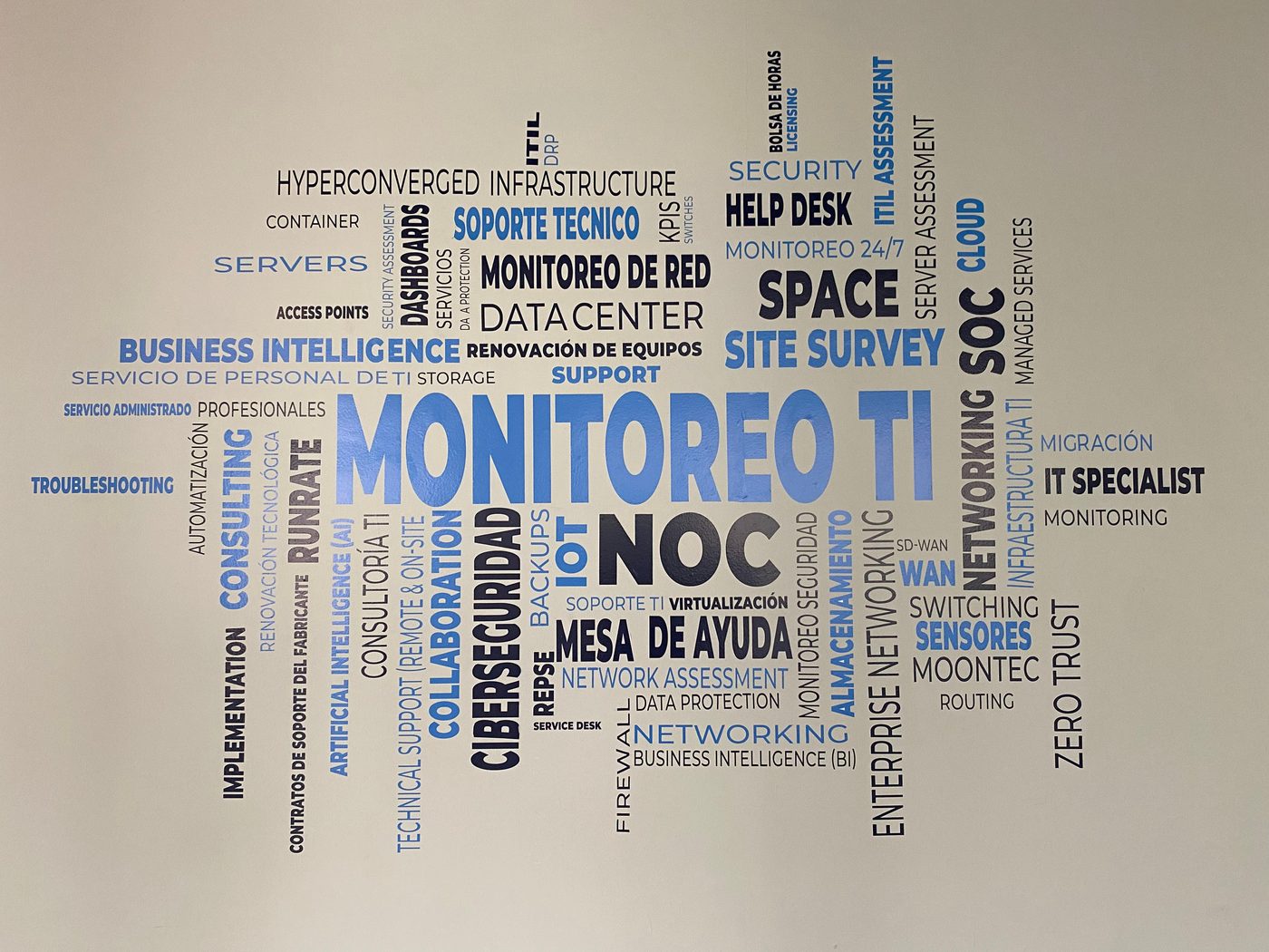 Mural de palabras 'MONITOREO TI' con vinil de corte azul y negro instalado por Punto Clave para APTEC en sus oficinas corporativas de Monterrey