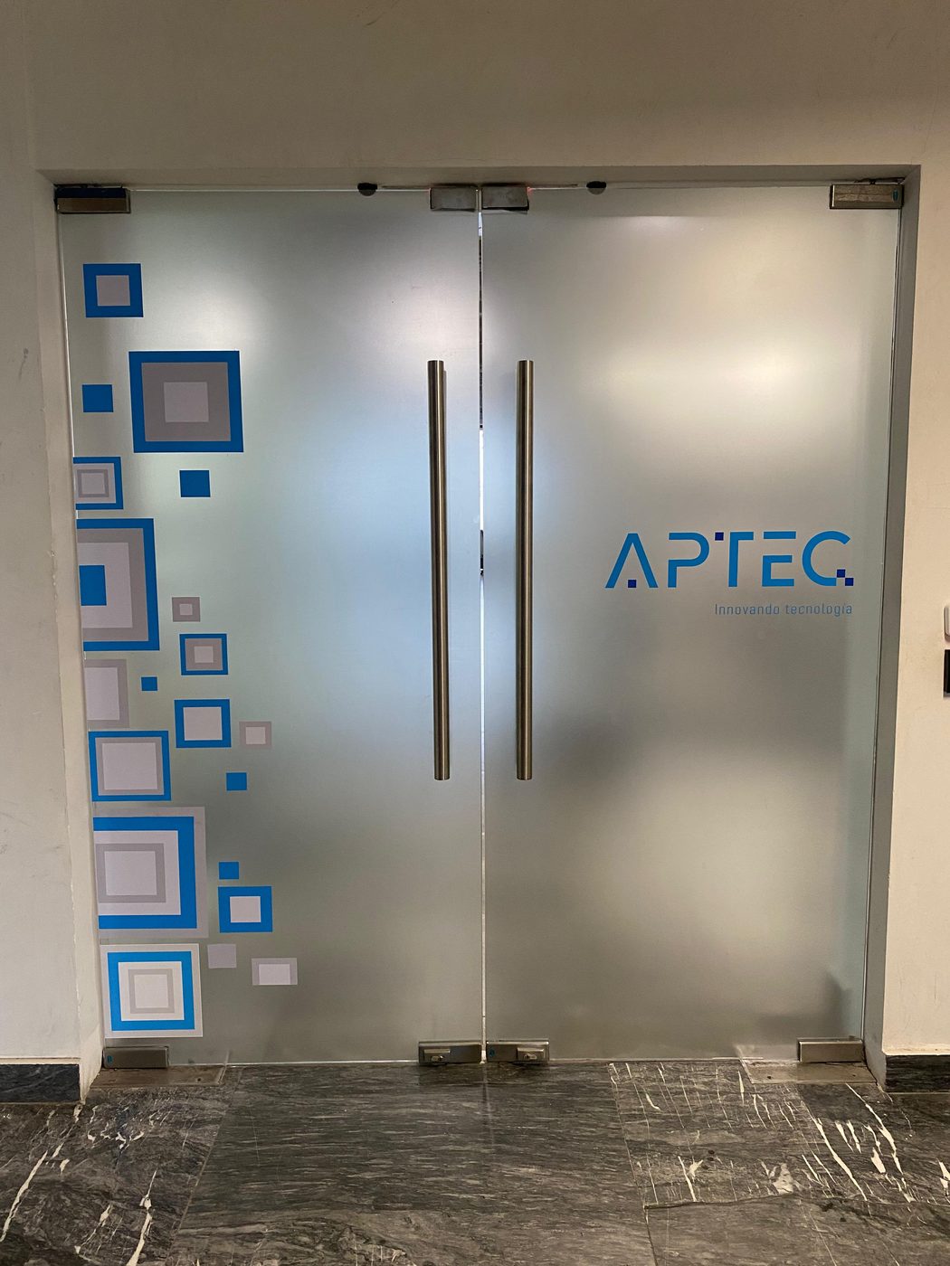 Puertas de vidrio con vinil esmerilado y logotipo corporativo APTEC instalado por Punto Clave en oficinas de Monterrey