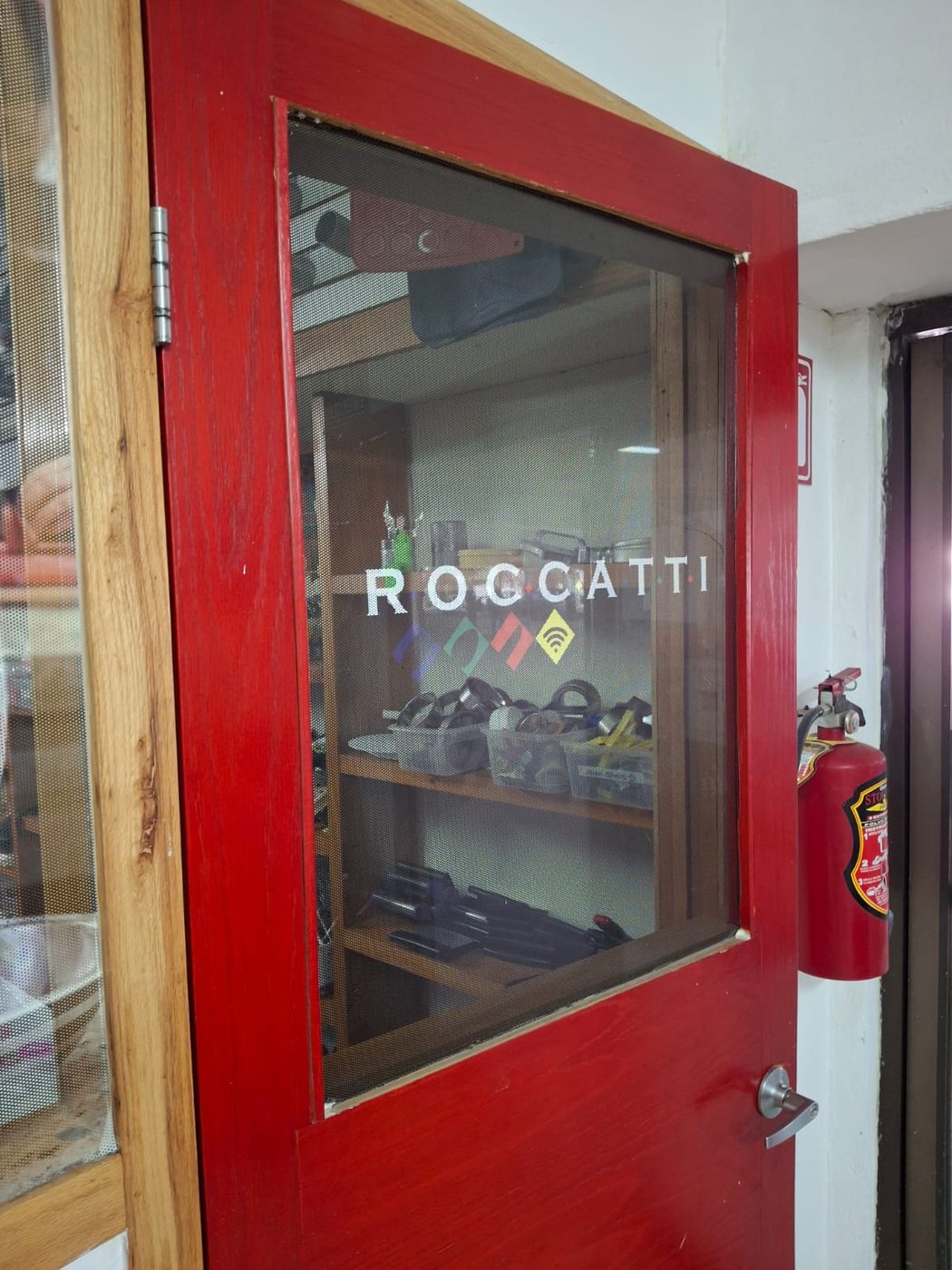 Logotipo ROCCATTI aplicado en vinil de corte blanco sobre cristal de puerta de acceso comercial roja instalado por Punto Clave en Monterrey