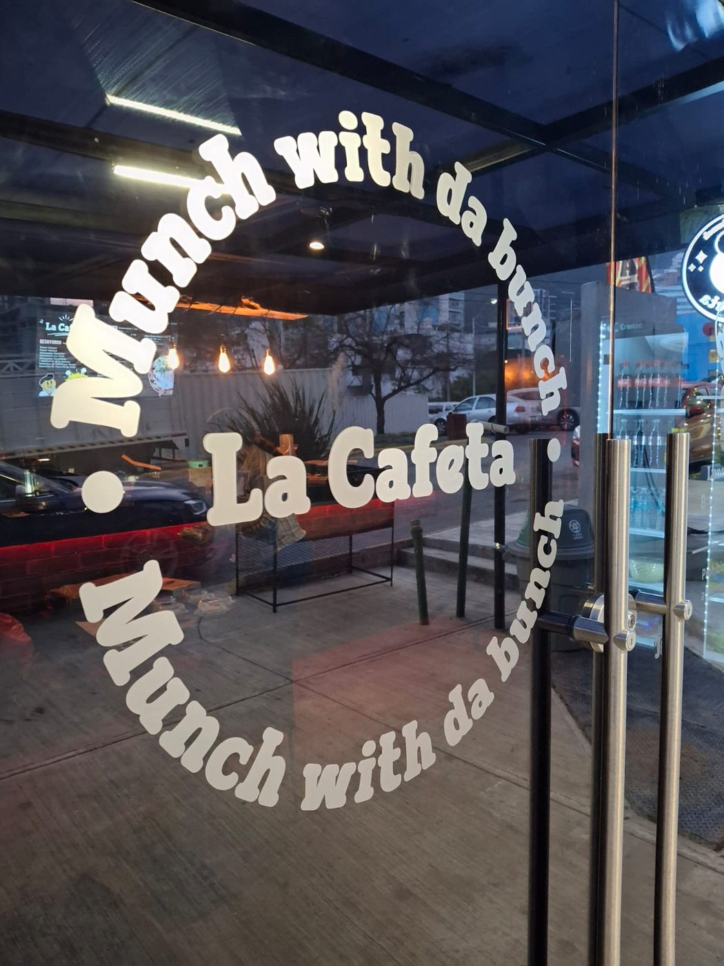 Rotulación de vidriera de cafetería La Cafeta con diseño circular 'Munch with da bunch' en vinil blanco sobre puerta de vidrio instalada por Punto Clave en Monterrey