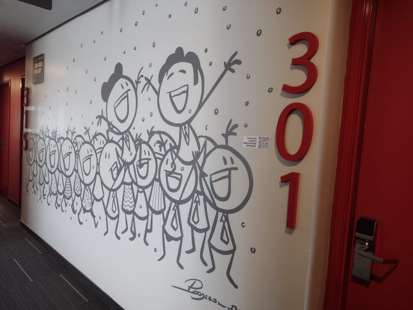 Mural ilustrado con grupo numeroso de personajes celebrando junto a letras 3D del número 301 en rojo, instalado en pasillo de hotel temático por Punto Clave
